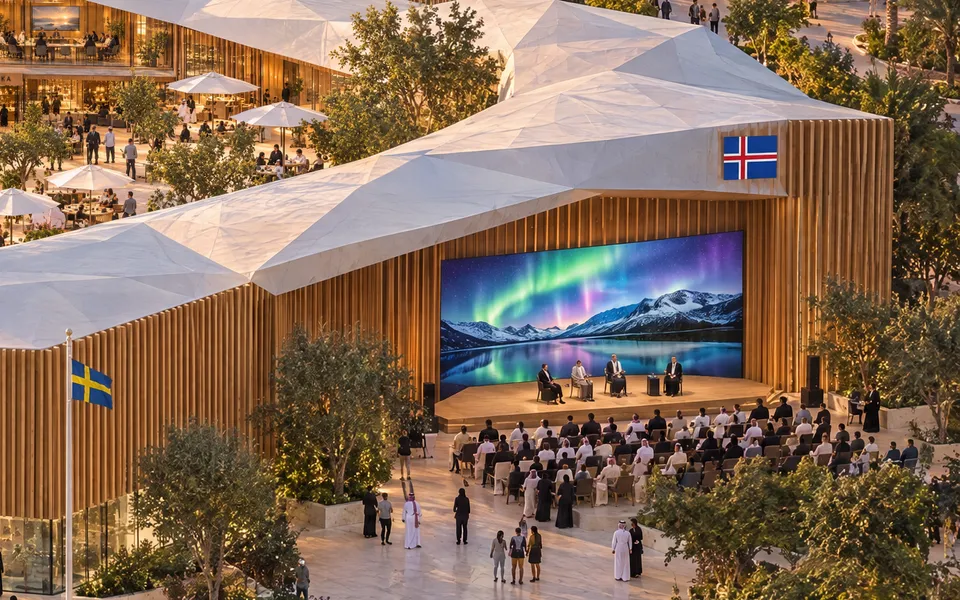 The outdoor stage: a large screen showing northern lights over mountains, a panel on stage and a seated audience, beside the timber facade.